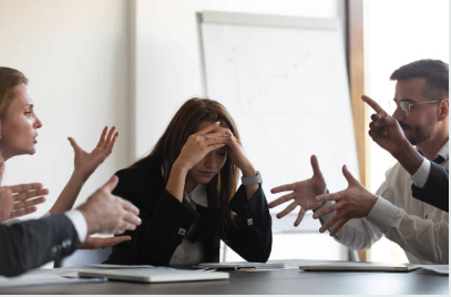 Woman frustrated in a meeting — hands up, pointing, everyone talking past each other
